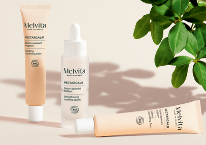 Focus sur les 3 produits de la gamme NectarCalm : s&eacute;rum, fluide et baume. Sur un fond blanc avec une petite plante sur le c&ocirc;t&eacute; droit