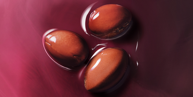 Trio de noix d'argan dans une mati&egrave;re huileuse sur un fond fuschia