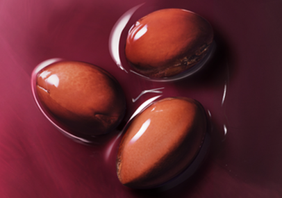 3 graines d'argan pos&eacute;es sur un liquide et un fond mauve