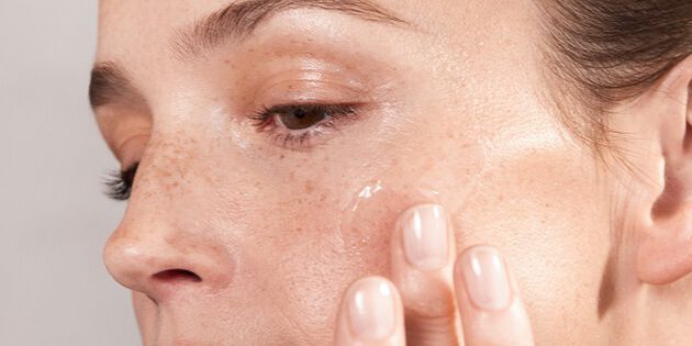 Femme se massant le visage avec un serum à l'acide hyaluronique