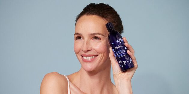femme qui tient une eau florale de bleuet dans la main