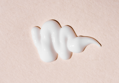 Zoom sur la texture d'une cr&egrave;me blanche sur un fond rose clair