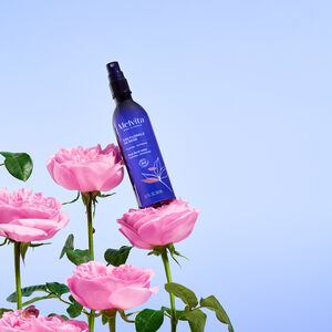 Eau Florale De Rose Bio en spray 200 ml, Le produit tient en diagonale sur deux roses sur un fond bleu clair | Melvita
