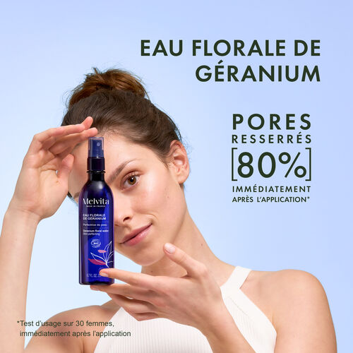 Agrandir la vue2/7 de Une femme tient entre ses deux mains devant son visage le produit. A droite "Eau florale de g&eacute;ranium&eacute;, en dessous "pores resser&eacute;s 90% imm&eacute;diatement apr&egrave;s l'application*". En bas "*Teste d'usage sur 30 femmes imm&eacute;diatement apr&egrave;s l'application"